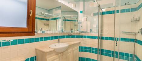 A bathroom with a sink, mirror, and shower.