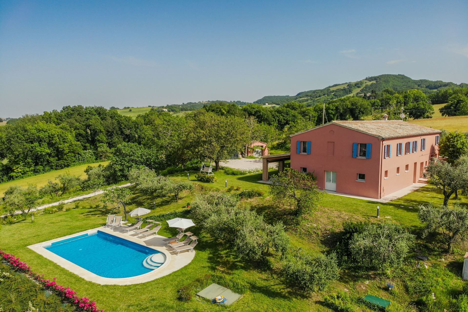 A house with a swimming pool, surrounded by lush greenery and hills.