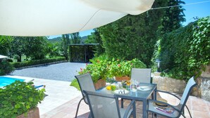 An outdoor patio with a table and chairs, surrounded by potted plants and a pool. - VILLA BENNASAR - RUSTIC STAY (Pollensa)