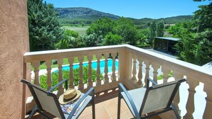 A balcony with two chairs, a hat, and a pool view. - VILLA BENNASAR - RUSTIC STAY (Pollensa)