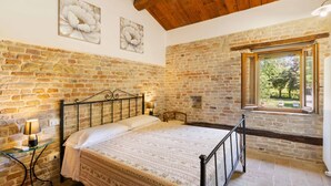 A bedroom with a stone wall, a bed, a window, and a lamp. - Villa delle Vigne, villa with large garden and pool, close to the Adriatic coast (Pesaro)
