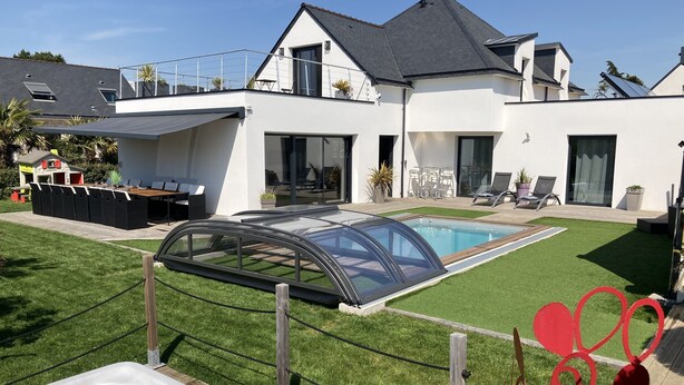 Una casa moderna con piscina, jacuzzi y patio trasero cercado.