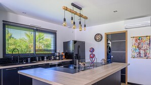 Una cocina moderna con una isla central, electrodomésticos negros y encimera de madera.