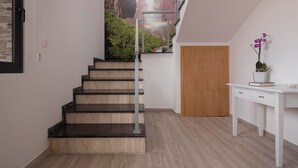 A staircase with dark steps leading to a landing, a wooden door, and a white desk with a plant. - 5-bed in Calheta, pool, gym, games room | Rosalina (Calheta)