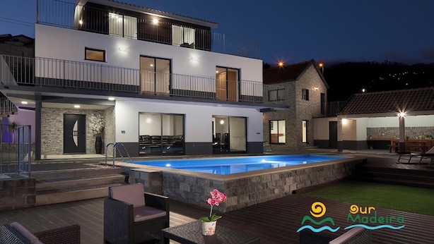 A modern two-story house with a swimming pool, outdoor seating, and a stone facade. - 5-bed in Calheta, pool, gym, games room | Rosalina (Calheta)