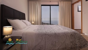 A bedroom with a large bed, a nightstand with a lamp, and a view of the sea through a balcony. - 5-bed in Calheta, pool, gym, games room | Rosalina (Calheta)