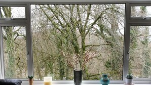 Un soggiorno moderno con un'ampia finestra, un tavolino da caffè grigio, un divano in pelle nera e un pouf lavorato a maglia.