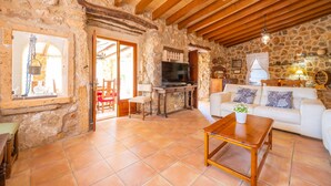 A rustic stone interior with a wooden ceiling, a television, a sofa, and a dining area. - CASA MARGARITA - Villa with private pool and free WiFi (Andratx)