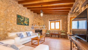 A stone-walled living room with a white sofa, wooden coffee table, and a fireplace. - CASA MARGARITA - Villa with private pool and free WiFi (Andratx)