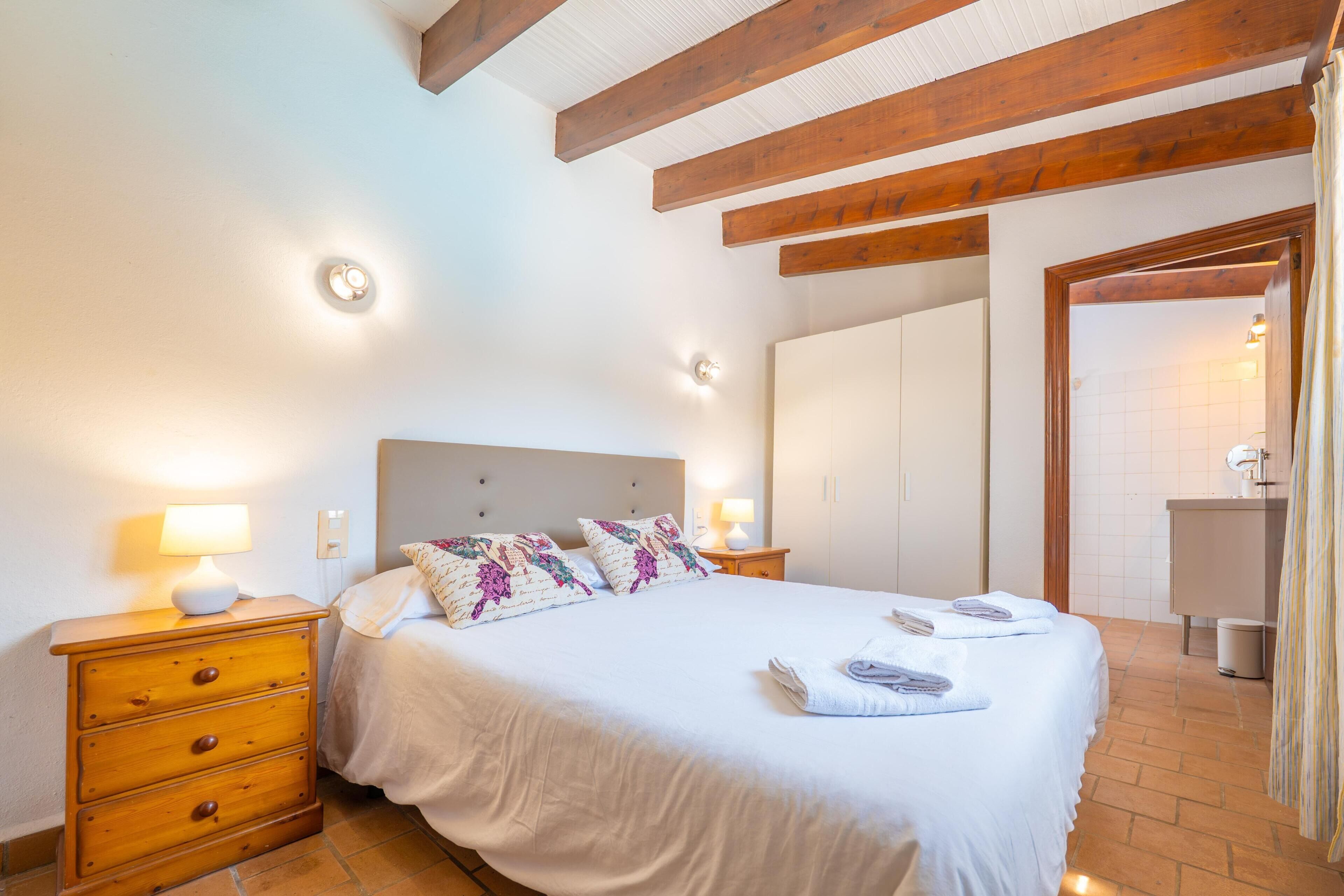 A bedroom with a bed, nightstands, a dresser, a bathroom with a sink, and a shower.