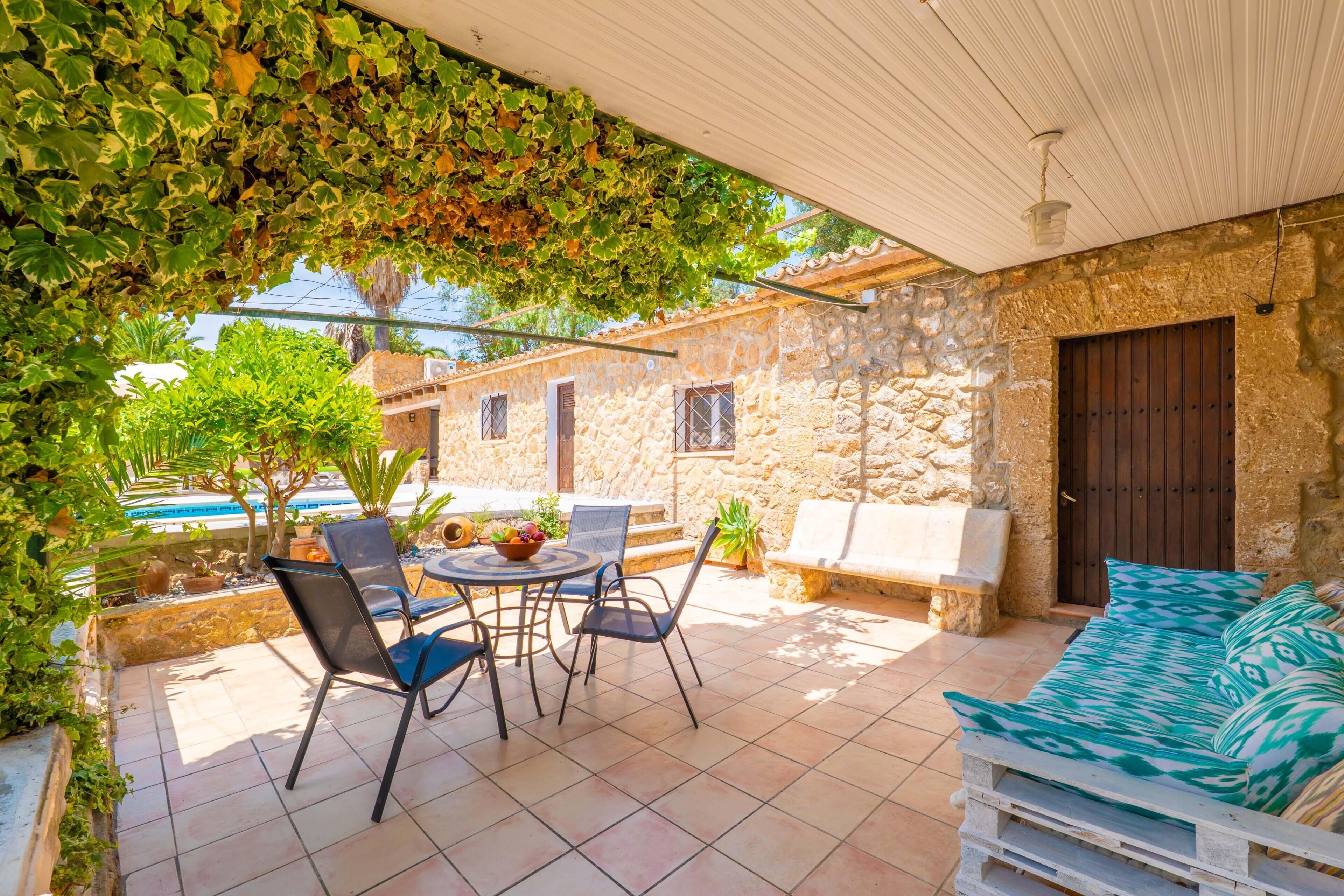 Un patio con mesa y sillas, un sofá y un muro de piedra.