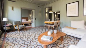 A hotel room with a patterned floor, a sofa, a desk with chairs, a lamp, and a bed. - Luxurious Oasis Paseo de Gracia (Barcelona)