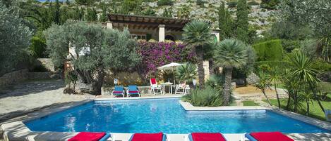 A pool area with lounge chairs and a view of a hillside.