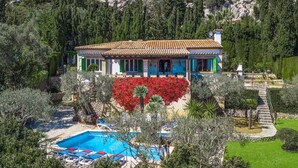 Eine Villa mit Swimmingpool, umgeben von üppiger Vegetation und einer felsigen Hanglage.