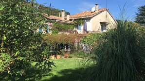 A house with a tiled roof, surrounded by lush greenery and a well-maintained garden.
