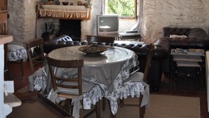 A rustic dining area with a stone wall, a fireplace, a television, and a cozy seating arrangement.