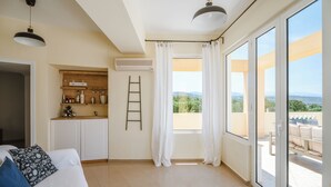 Una stanza con un letto, un angolo cottura con scaffali, una scala e una vista attraverso ampie finestre.
