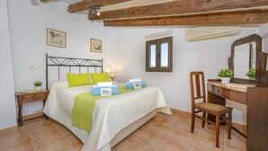 Ein Schlafzimmer mit Bett, Schreibtisch, Stuhl, Fenster und einer Klimaanlage.