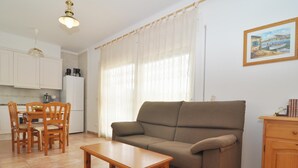 Ett vardagsrum med en soffa, ett träbord och en matplats med stolar.