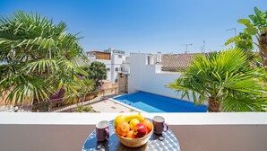 A balcony with a pool, surrounded by palm trees and a view of a white building. - Modern downtown apartment [28] (Lagos)