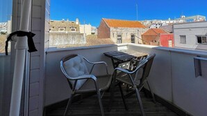 A balcony with two chairs and a table, overlooking a cityscape with buildings and a clear blue sky. - Sofeelings Estudio Sol, Baixa de Albufeira (Albufeira)