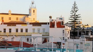 A hotel with a white facade, a bell tower, and a pool area with lounge chairs. - Sofeelings Estudio Sol, Baixa de Albufeira (Albufeira)