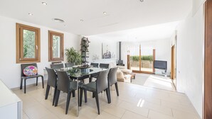 Un salón espacioso con una mesa de comedor, sillas, un sofá y un televisor.