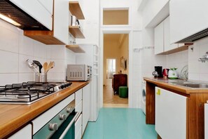 A compact kitchen with a gas stove, microwave, and wooden countertop.