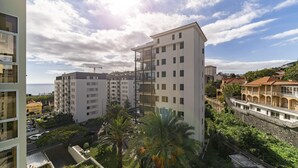 A multi-story residential building with balconies, surrounded by greenery and other buildings. - Ilhéus III, quiet place in the city center (Funchal)