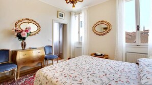 Een hotelkamer met een bed, een kaptafel, een stoel, een spiegel en een raam met uitzicht.