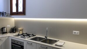 Een moderne keuken met een gasfornuis, een dubbele spoelbak, oven en een raam boven de spoelbak.