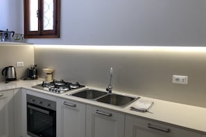 Eine moderne Küche mit Gasherd, einer doppelten Spüle, einem Backofen und einem Fenster über der Spüle.