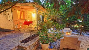 An outdoor patio with stone flooring, a dining table with chairs, a potted plant, and a lantern.
