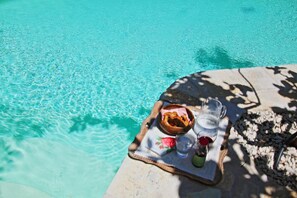 Una bandeja con comida y bebidas junto a una piscina.