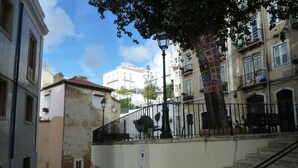 A staircase leading up to a building with a tiled facade, a metal railing, and a tree with colorful decorations.