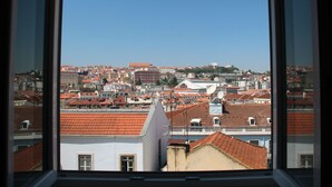 A view from a window overlooking a densely packed urban area with red-tiled roofs and various building styles.