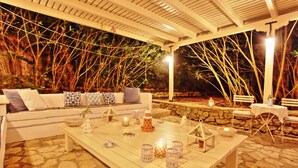 An outdoor seating area with a white sofa, stone flooring, and lanterns. - Lili Luxury Cottage: Pool, A/C, Wi Fi, lovely gardens (Ozias Gaios)