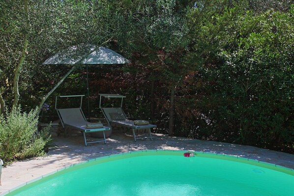 A swimming pool with two lounge chairs and an umbrella.