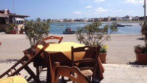 A seaside restaurant with outdoor seating, a view of the water, and buildings in the background. - Large trullo/ villa, with private 10x4 m pool, in olive grove 2km from town (Ceglie Messapica)