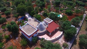 An aerial view of a property with a central building featuring a dome and a red-roofed structure, surrounded by trees and a small pool. - Large trullo/ villa, with private 10x4 m pool, in olive grove 2km from town (Ceglie Messapica)