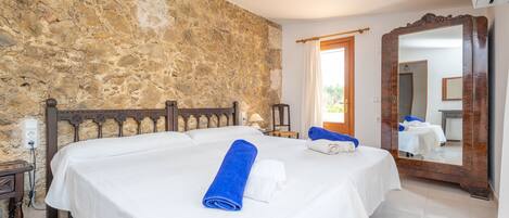 Ein Schlafzimmer mit Stehwand, einem großen Spiegel und einem Bett mit weißen Leinen und blauen Handtüchern.
