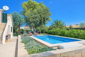 A swimming pool with a stone border, a staircase, and a satellite dish on a building. - EL LAGO for 6 people 900m from the beach (Alcúdia)