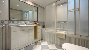 Ein Badezimmer mit gefliestem Boden, einem Waschbecken, einem Spiegel und einer Duschkabine.