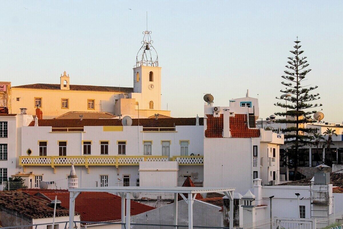 A building with a clock tower, satellite dishes, and a pine tree.