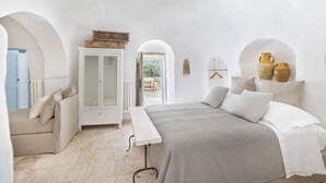 A bedroom with a bed, a bench, a cabinet, and a view of the outdoors. - Charming Trullo Amarcord with Private Pool, Spa & Park near Alberobello (Selva di Fasano)