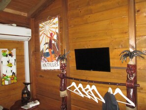 Un interior de madera con un televisor con marco de madera, un perchero en la pared y un cartel con la palabra