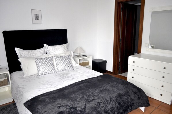 A bedroom with a bed, a nightstand, a dresser, and a door. - Refúgio Guest House, your Home Away Retreat with amazing gardens and sceneries (São Vicente. Madeira)