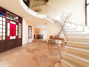 Un interior espacioso con una escalera curva, un comedor y vistas al exterior.
