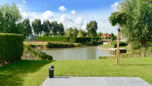 A riverside walkway with a paved path, a small bridge, and a dock extending into the water.