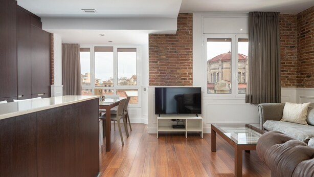 Una sala de estar moderna con televisor, sofá y comedor.